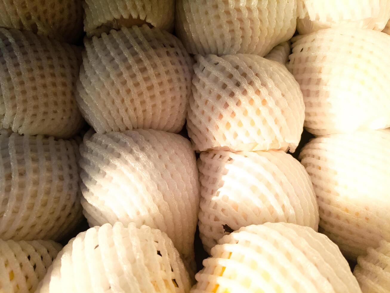 pile of fresh pears wrapped in fruit net at market photo