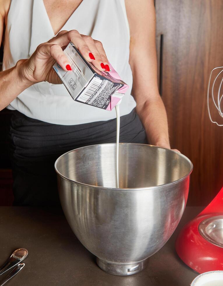 Woman Pouring Cream into Mixing Bowl photo