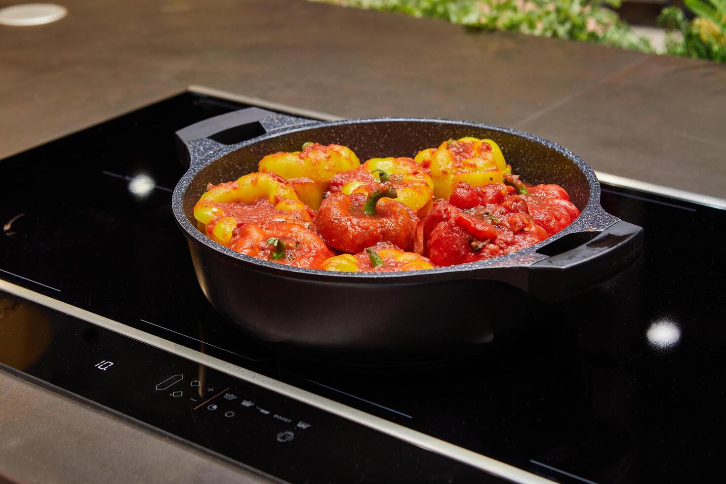 Stuffed peppers with a mixture of rice, lentils and vegetables in a frying pan on an induction cooker in a home kitchen photo
