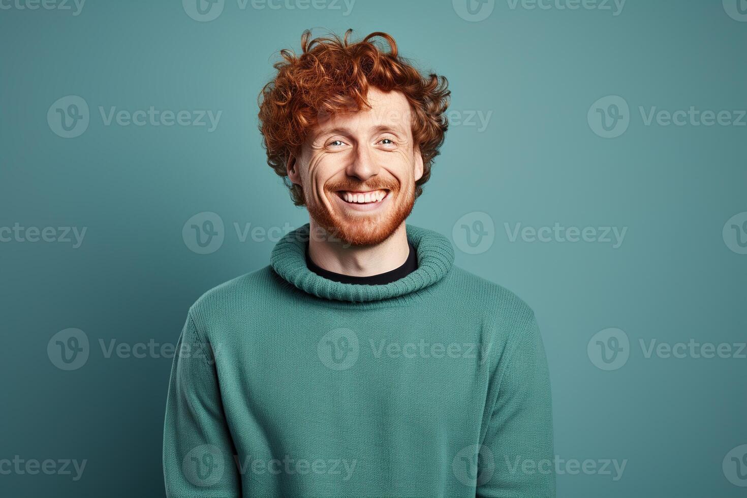 portrait of smiling handsome young man with ginger curly hair in sweater on blue background photo