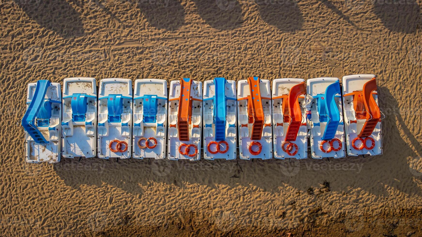 Top view of pedal boats along the beach with the sea. Aerial view of Mediterranean beach with sand and umbrellas. Colorful summer background expressing relaxation, summer vibes, sea, vacation, travel. photo