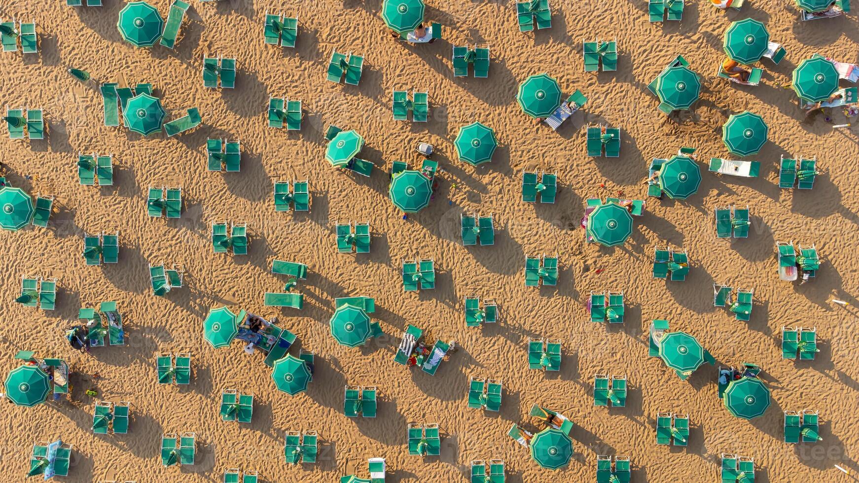Top view of colorful umbrellas on the beach. Aerial view of a pattern of summer, relaxation, tourism, summer vibes. Top view of Italian and European beaches, beach and Mediterranean summer. photo