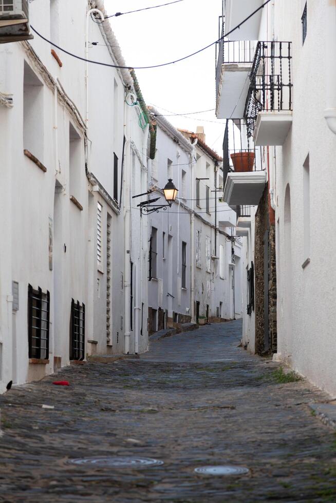 Narrow cobblestone street featuring white buildings and balconies in spain photo