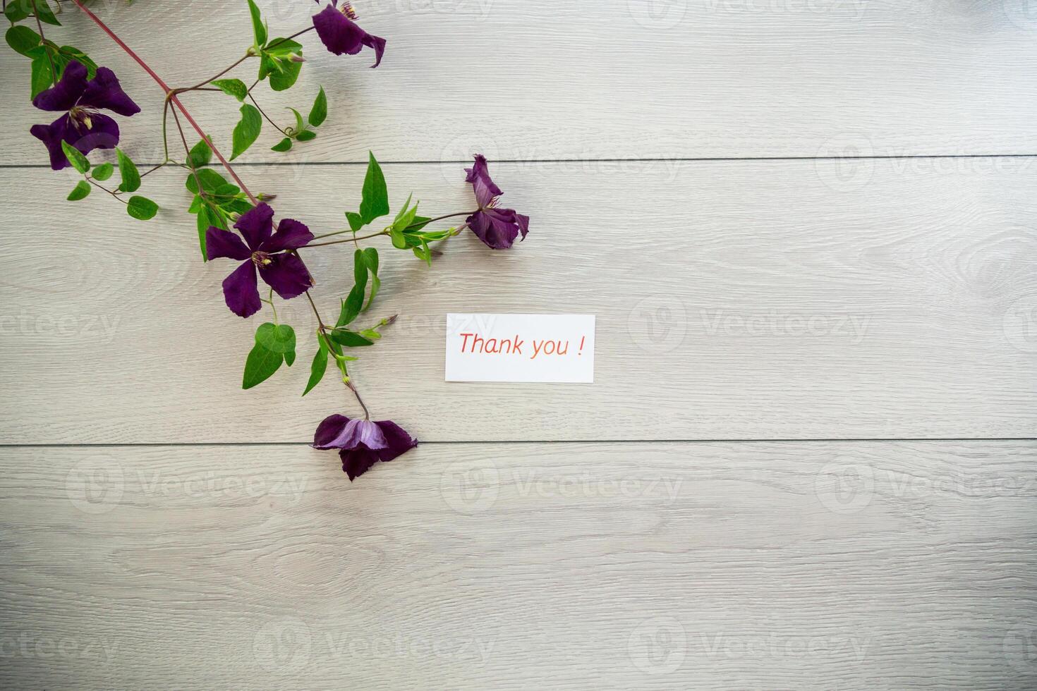 branch of blooming purple clematis, on a light wooden table photo