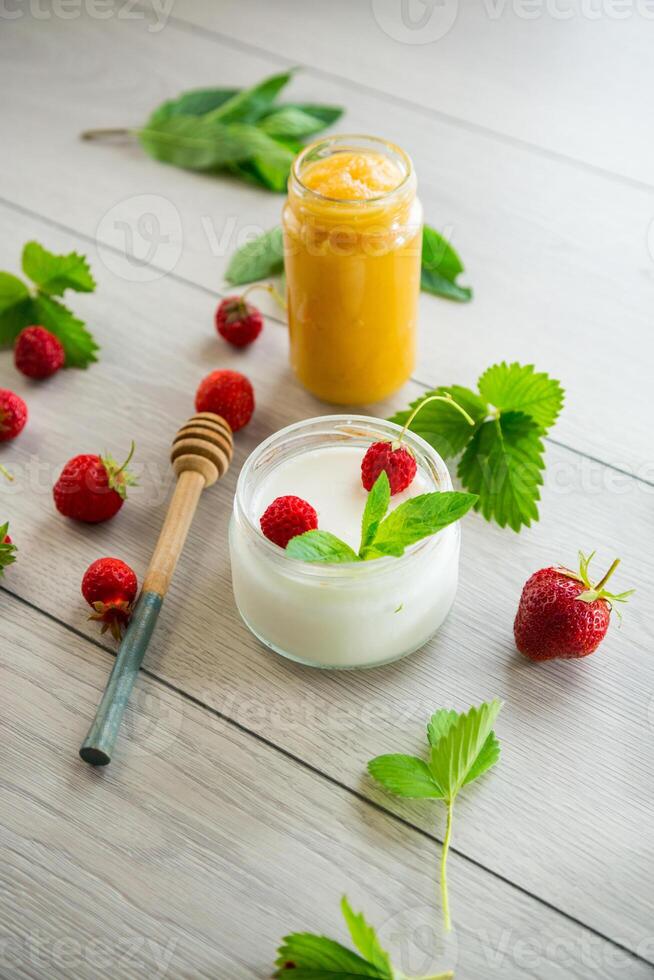 homemade sweet yogurt in a jar with strawberries, on a wooden table photo