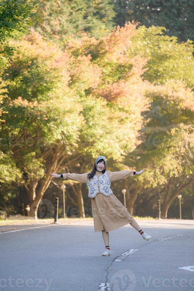 Seasonal delight, Asian woman in a casual dress enjoys fall in Japan. Elegant portrait with colorful maple foliage, capturing her cheerful smile and the beauty of the changing season. photo