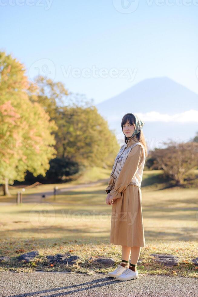 Seasonal delight, Asian woman in a casual dress enjoys fall in Japan. Elegant portrait with colorful maple foliage, capturing her cheerful smile and the beauty of the changing season. photo
