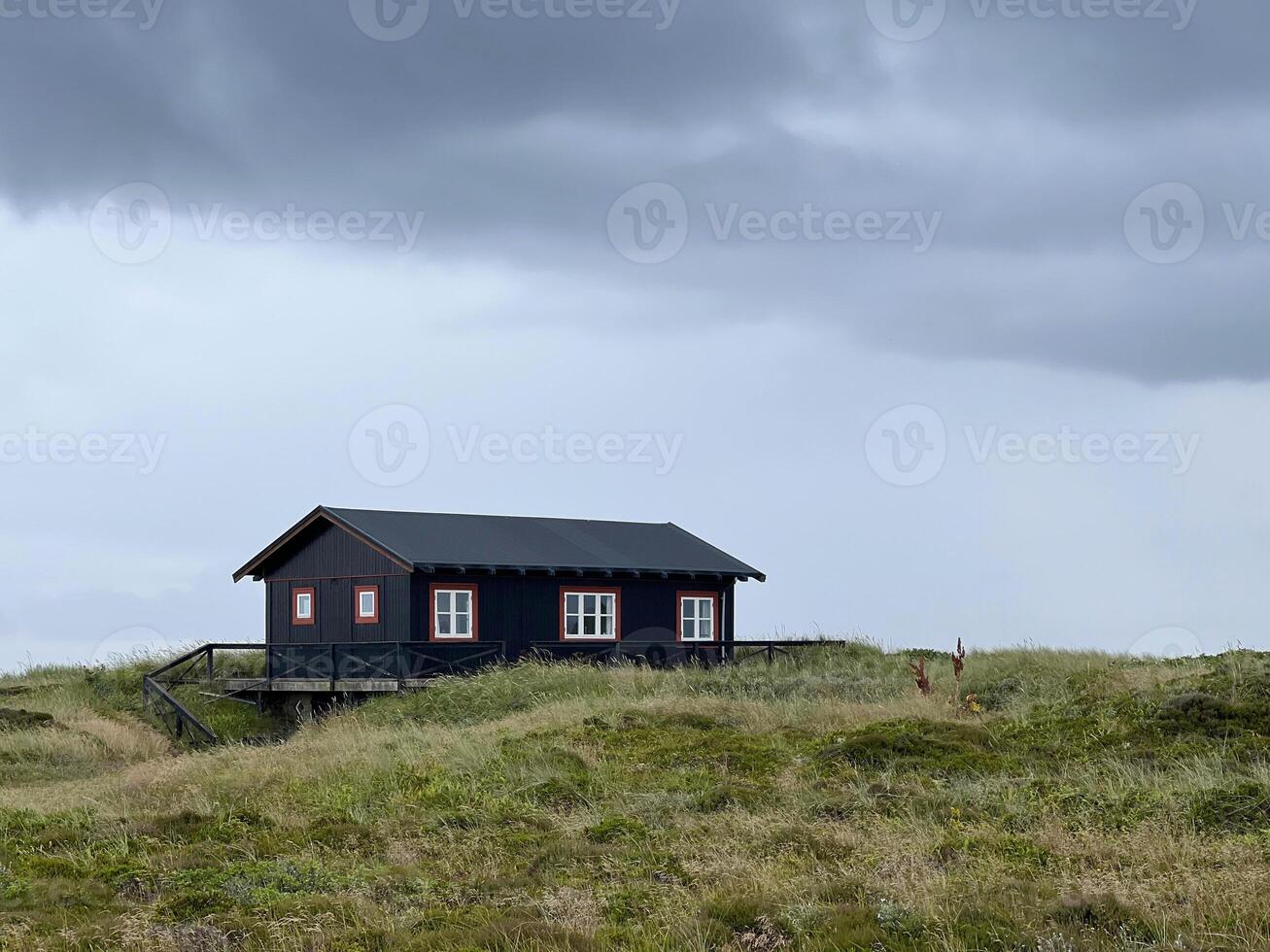 A lonely picturesque house in Danish style on a meadow under the dark cloudy sky before rain, Skagen, on the way to the cape Grenen photo