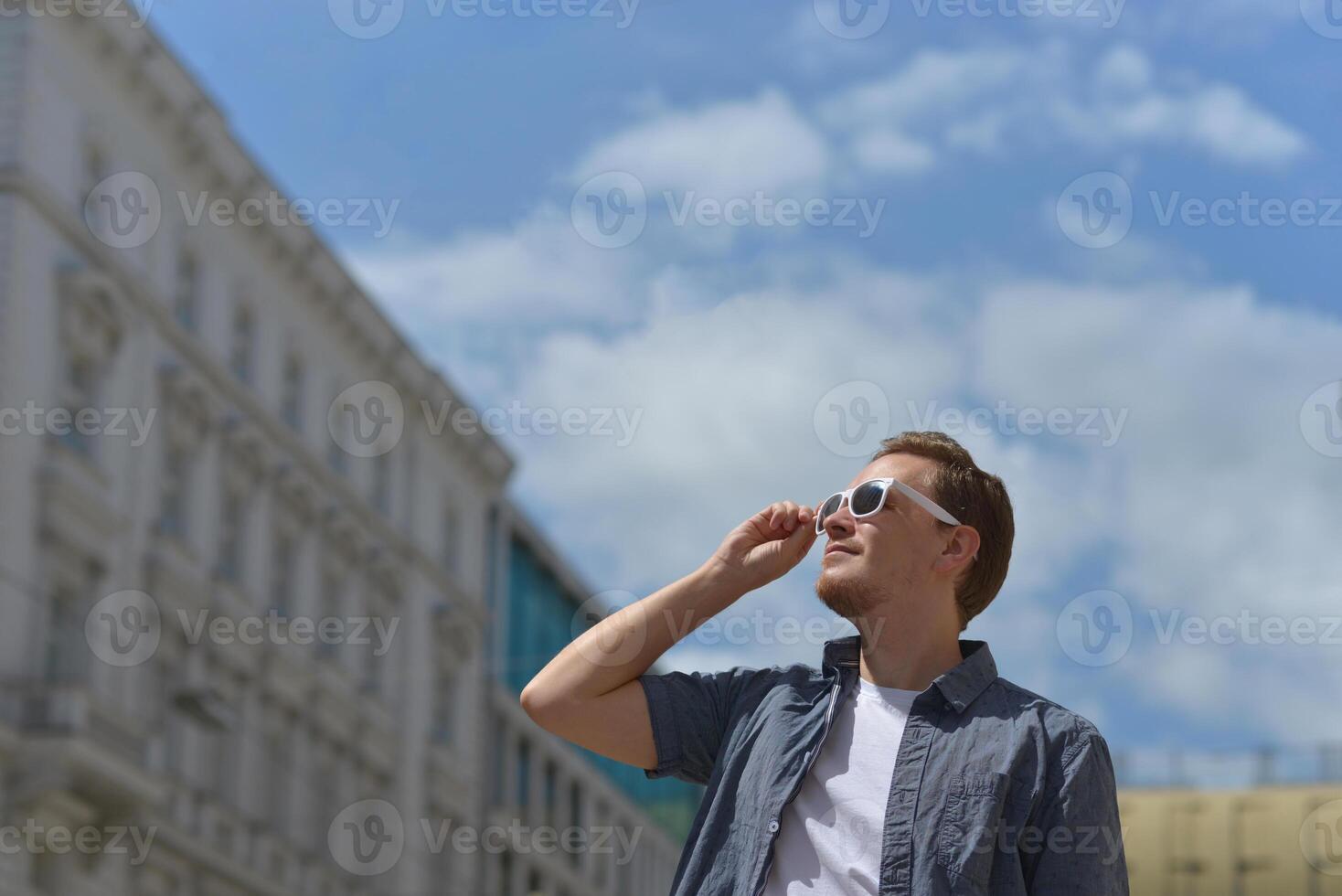 A man wearing sunglasses on the street in Vienna. The concept of hot sunny weather in the city. A man suffers from the heat photo