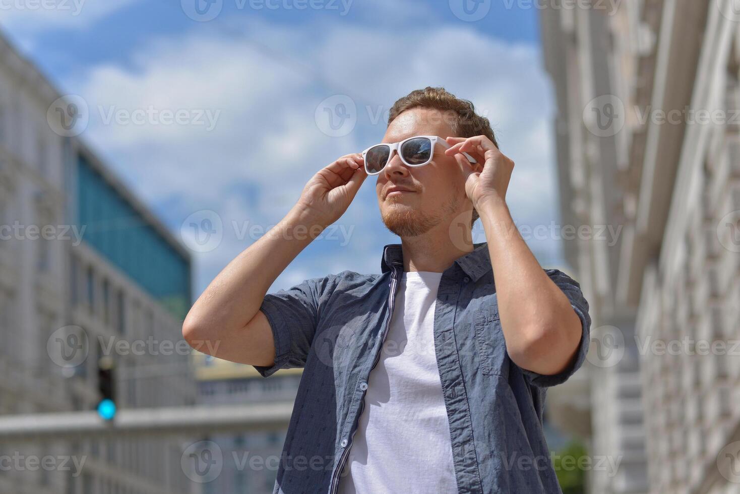 A man wearing sunglasses on the street in Vienna. The concept of hot sunny weather in the city. A man suffers from the heat photo