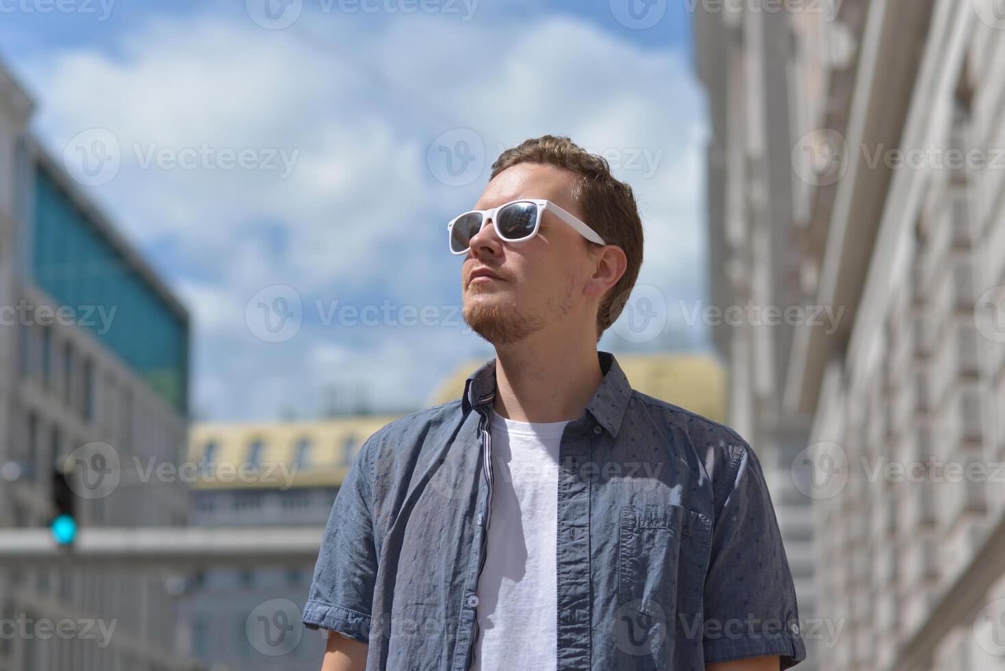 A man wearing sunglasses on the street in Vienna. The concept of hot sunny weather in the city. A man suffers from the heat photo