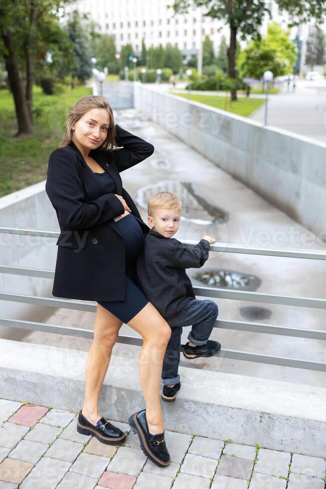 Pregnant mother and her little son walking and funny spending time together photo
