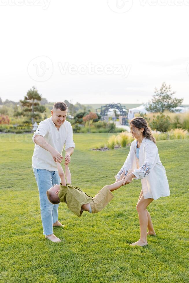Parents Are Spending Quality Time With Their Son at the Park, Laughing and Playing Together on a Bright and Sunny Day photo
