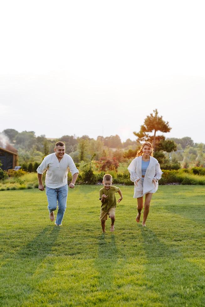 A Family Joyfully Running Across a Lush Green Grass Field on a Warm Summer Day, Basking in the Sunshine and Laughter photo