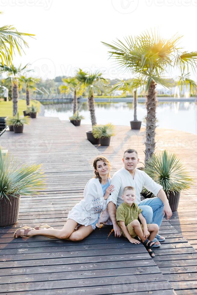 A Charming Family Portrait Captured Against the Backdrop of a Serene Wooden Deck Overlooking a Peaceful Lake photo