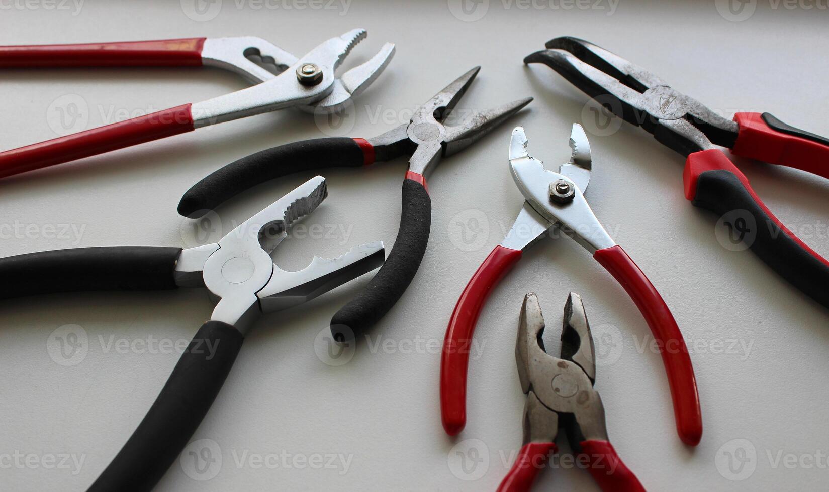 Set Of Different Types Of Mechanics Pliers On White Surface photo