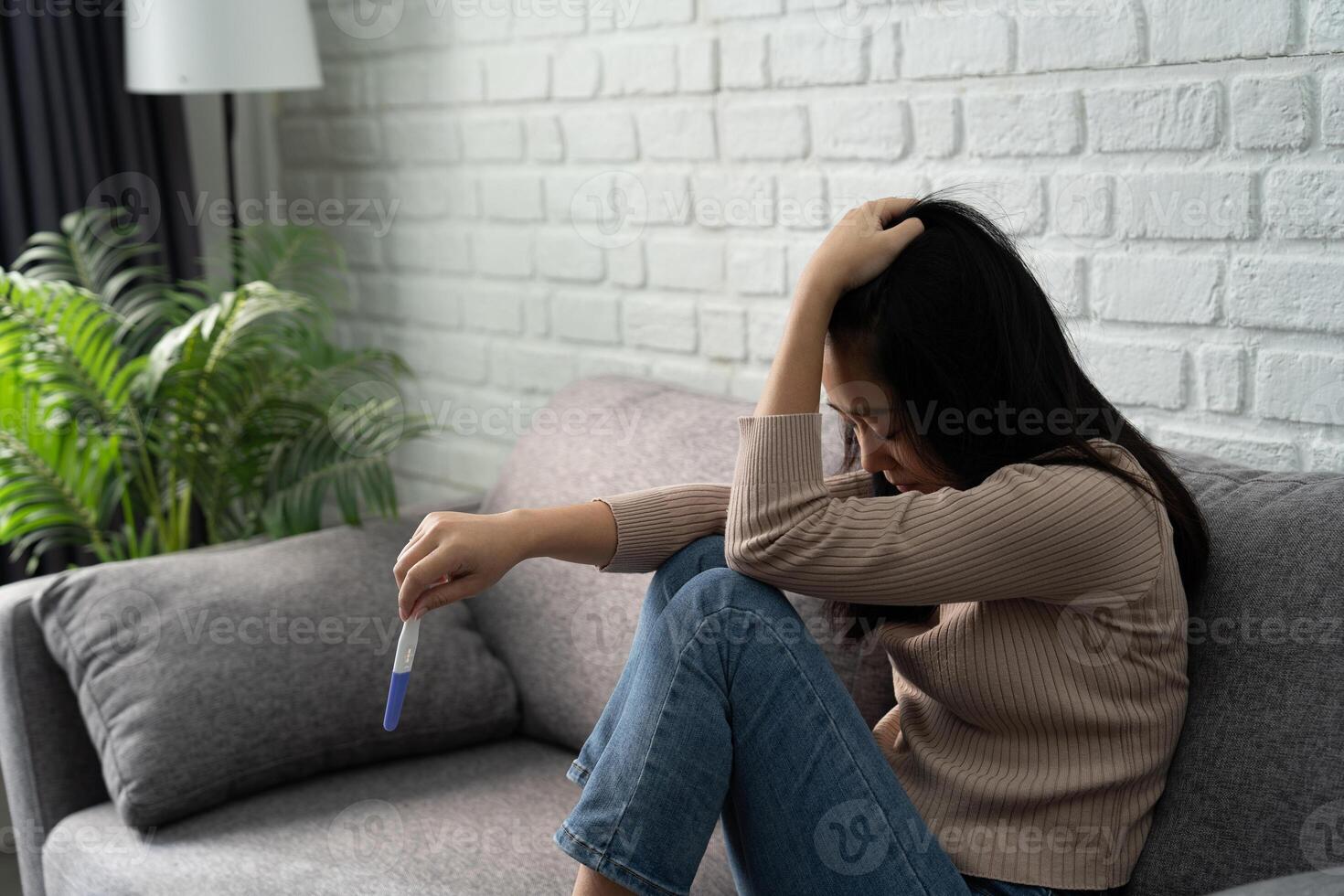Asian woman holding pregnancy test kit, disappointed with negative result. She was unwilling to become pregnant. photo