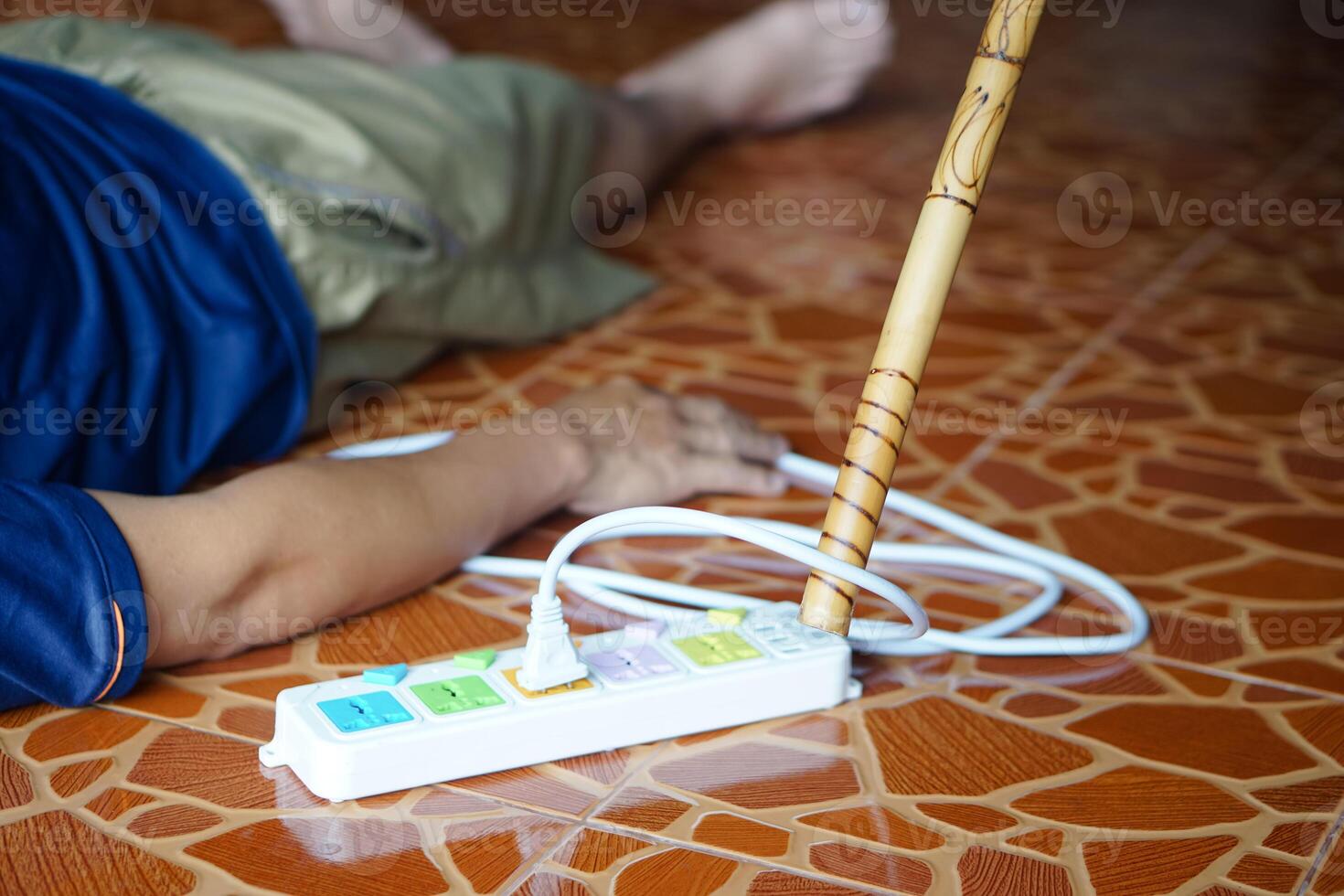 Using wooden stick is moving away the electric plug socket from the unconscious man who lay down on the floor. Concept, Electric Shock. Emergency basic rescue. First Aid photo