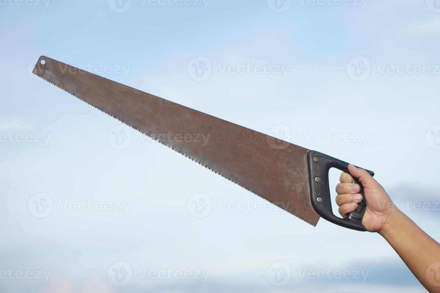 Close up carpenter hand holds old saw. Concept, tool for cutting. Carpentry , woodwork and construction work tool. Carpentry. use for cutting wood. Handsaw for carpenter. photo