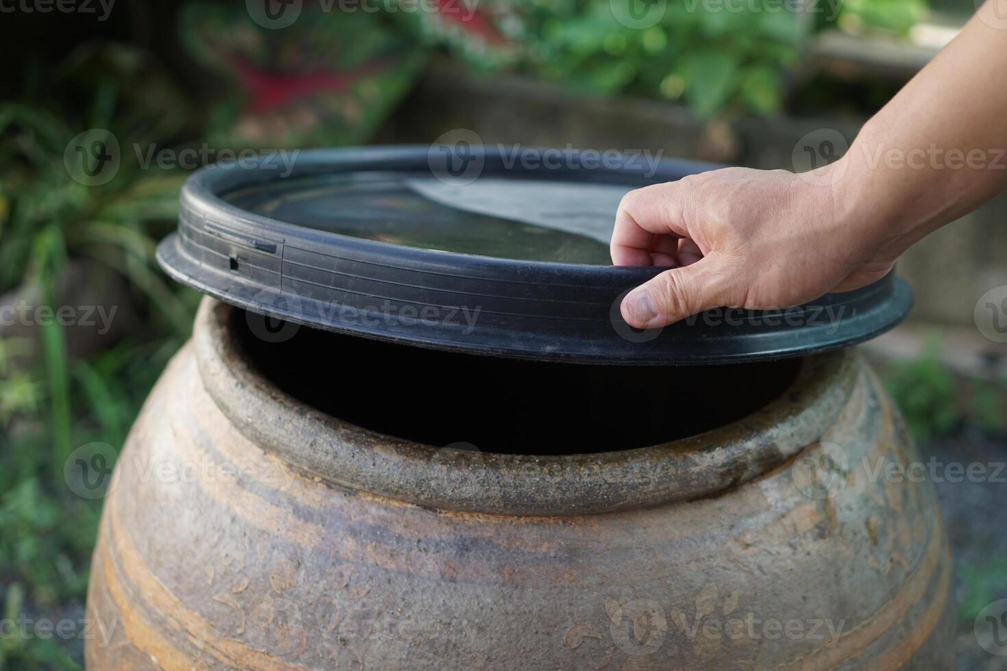 Closeup hands hold lid to cover water jar to protect from mosquitoes to breed inside or other insects or dust go into water. Concept, campaign to stop mosquitoes cycle to lay eggs in water container photo