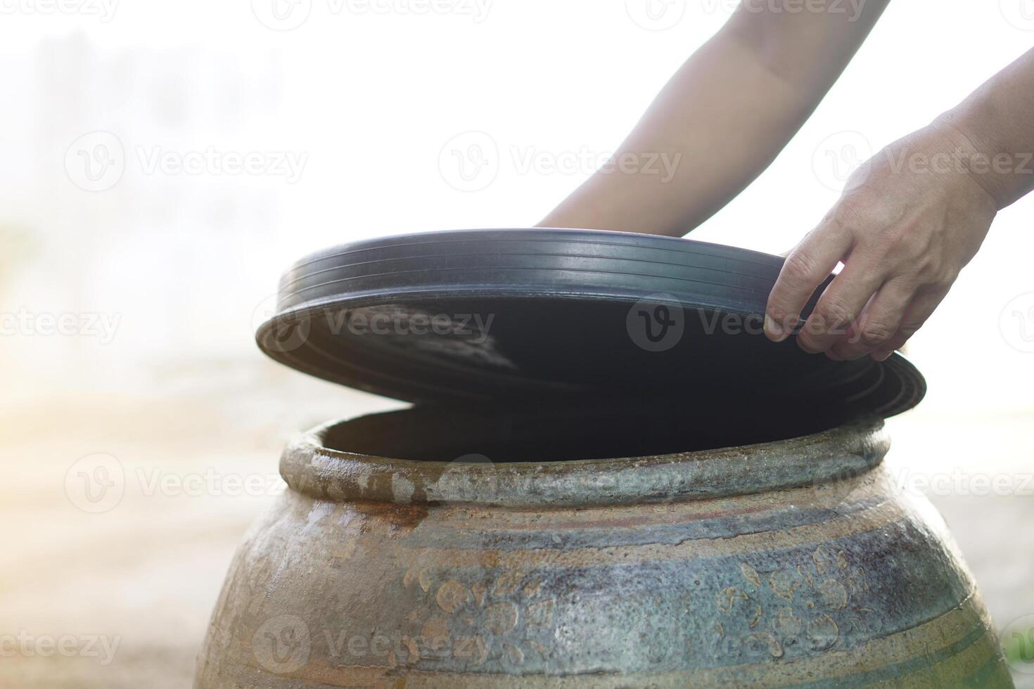 Closeup hands hold lid to cover water jar to protect from mosquitoes to breed inside or other insects or dust go into water. Concept, campaign to stop mosquitoes cycle to lay eggs in water container photo