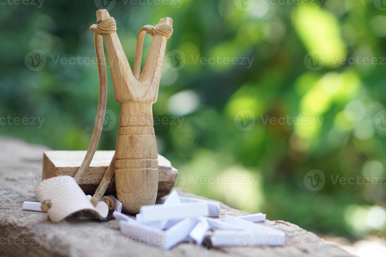 Handmade wooden slingshot, a Y shaped stick with elastic between the arms. used to propel small stones Thai traditional weapon that use to shoot birds, fish , for fight game or other purposes. photo