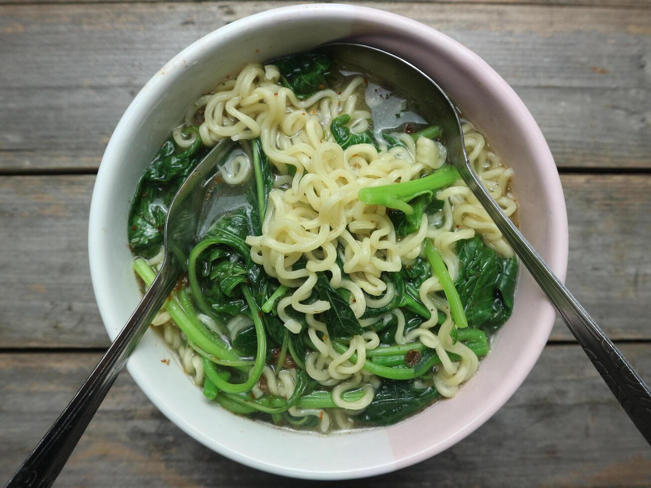 Instant noodle soup with vegetables in a bowl on a gray background photo