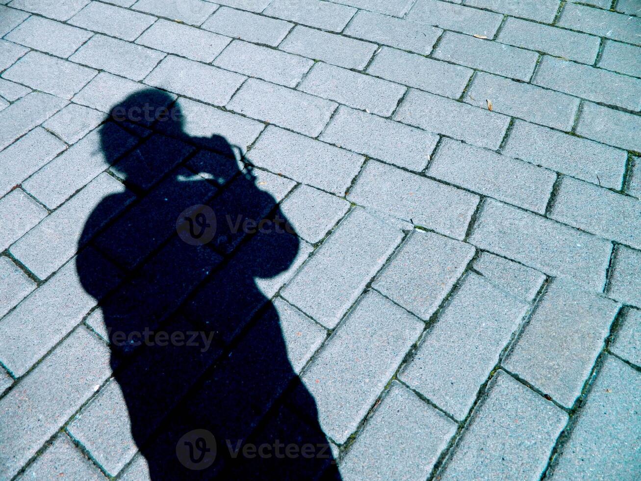 silhouette shadow of a girl with a camera on the background of road masonry photo