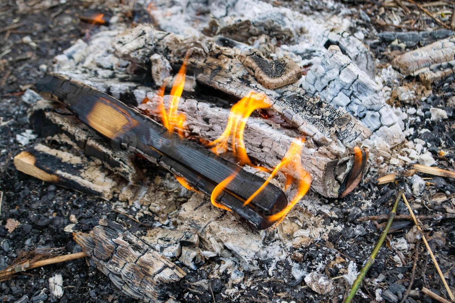 A fire burns in a campfire with a red fire in the background. photo
