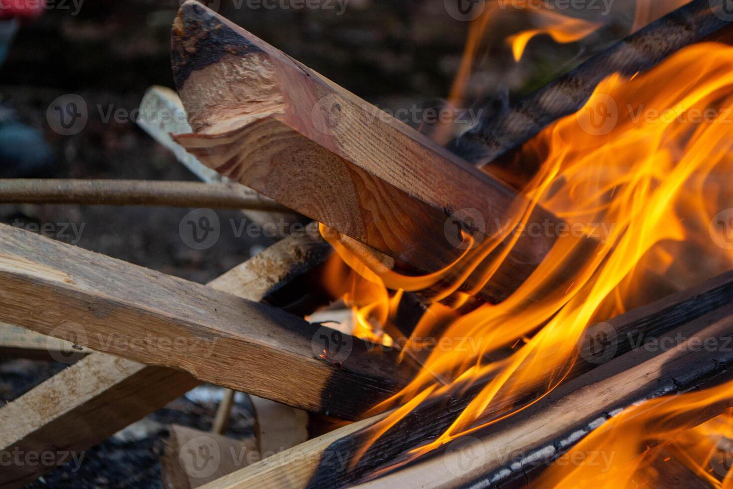 A fire burns in a campfire with a red fire in the background. photo