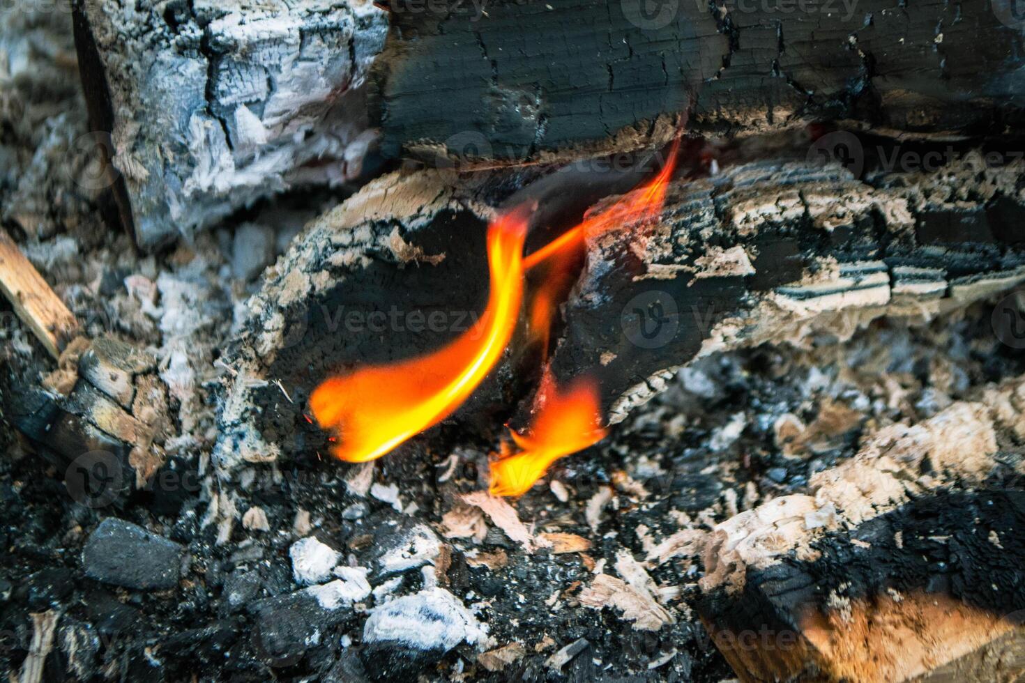 A fire burns in a campfire with a red fire in the background. photo