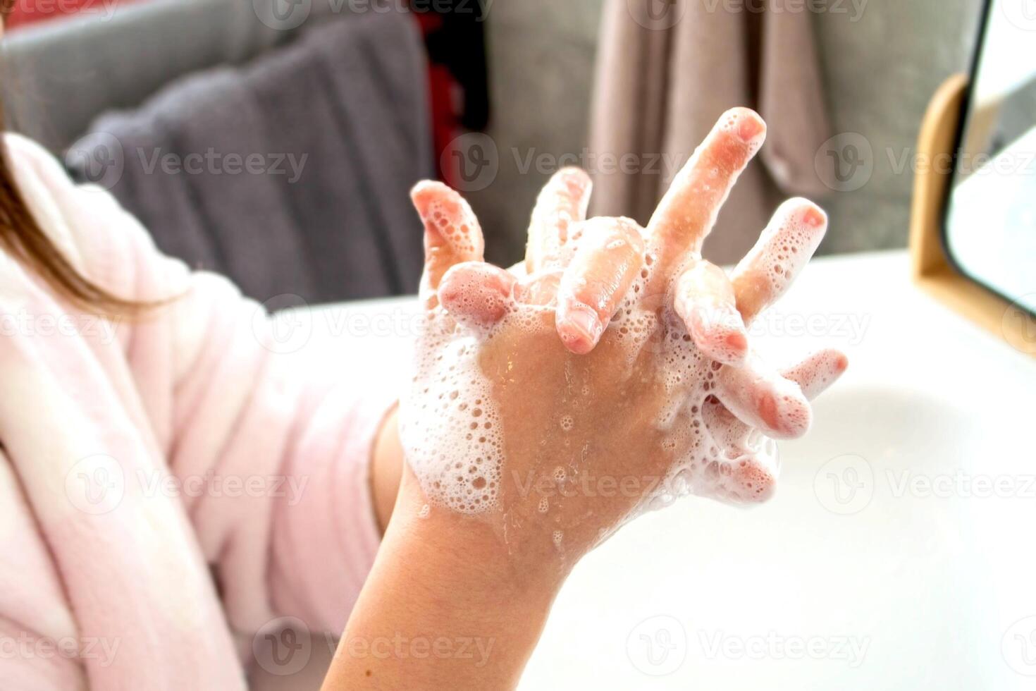Girl washing hands with water and soap in bathroom photo