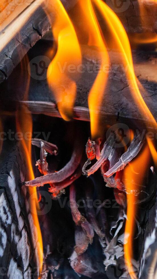 A fire burns in a campfire with a red fire in the background. photo