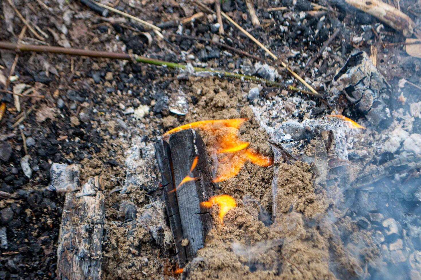 A fire burns in a campfire with a red fire in the background. photo