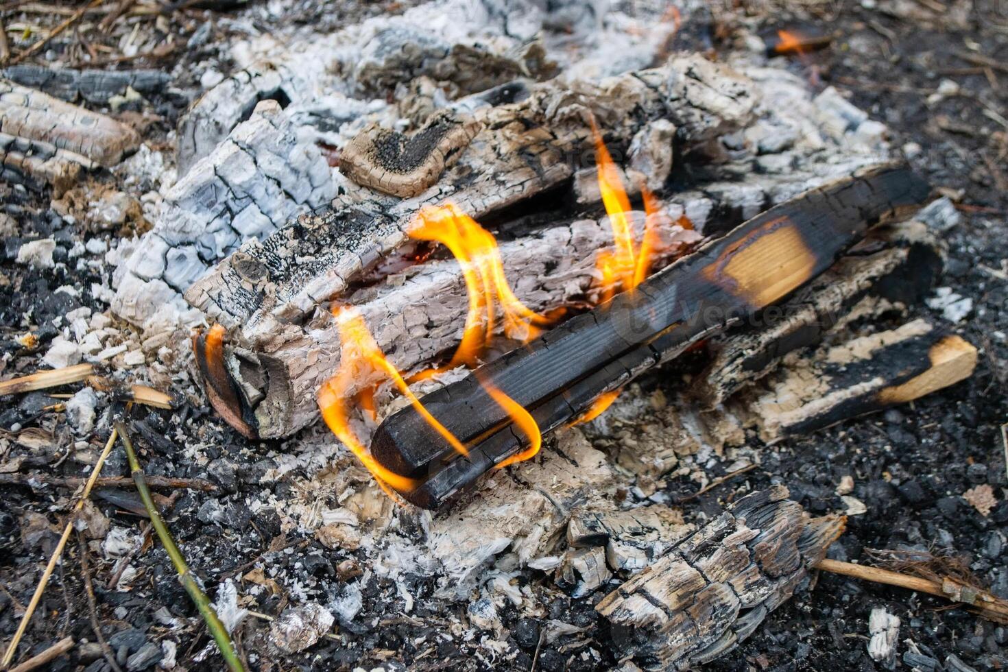 A fire burns in a campfire with a red fire in the background. photo