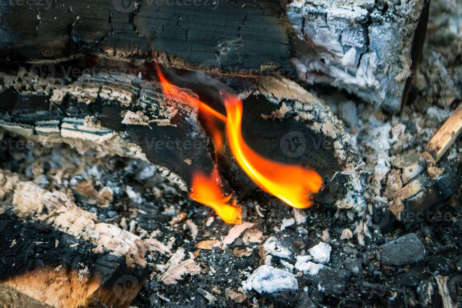 A fire burns in a campfire with a red fire in the background. photo