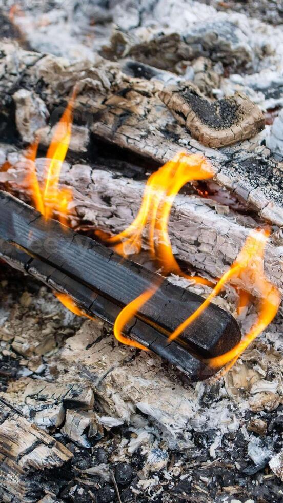 A fire burns in a campfire with a red fire in the background. photo