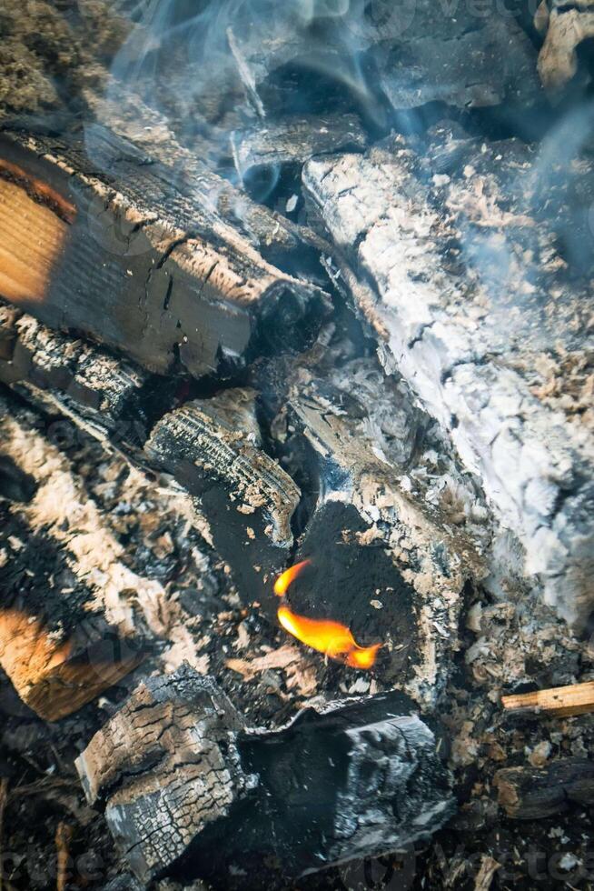 A fire burns in a campfire with a red fire in the background. photo