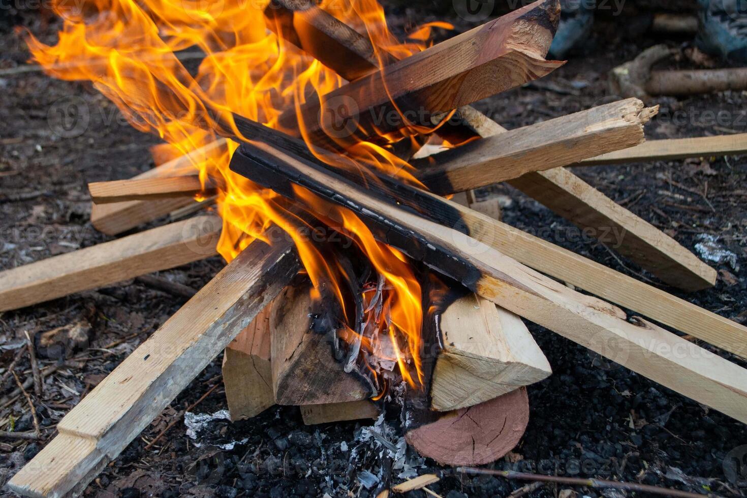 A fire burns in a campfire with a red fire in the background. photo