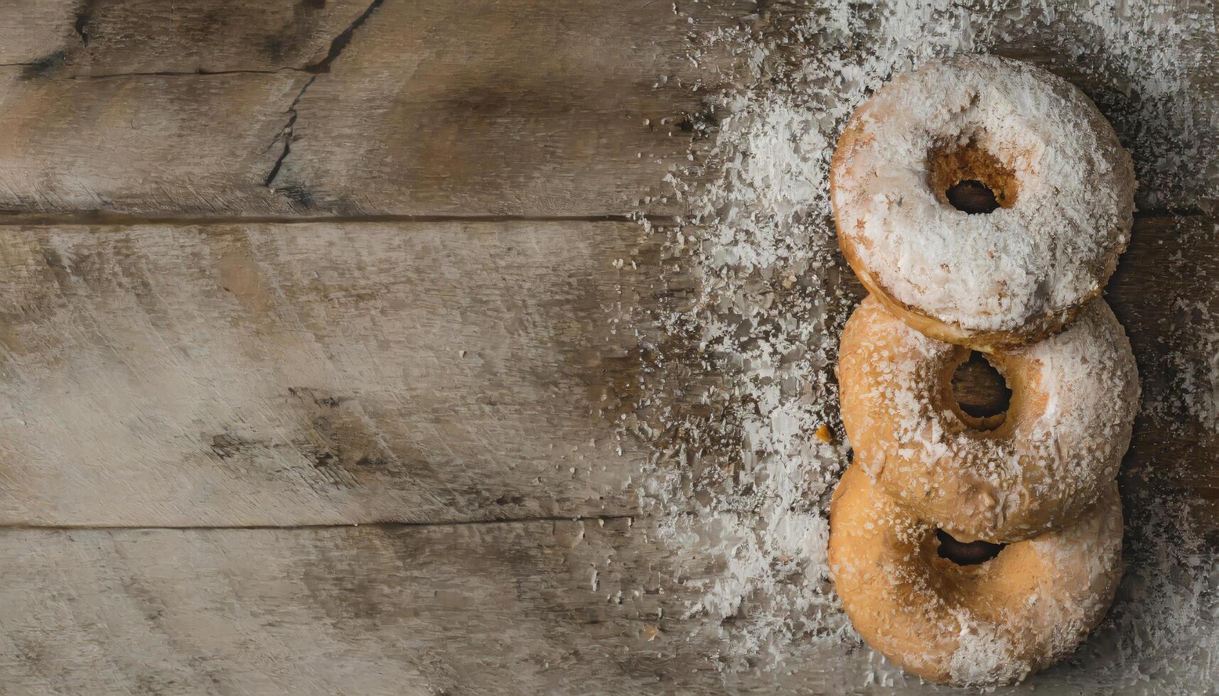 Copy Space image of Donuts with powdered sugar on wooden table on black background photo
