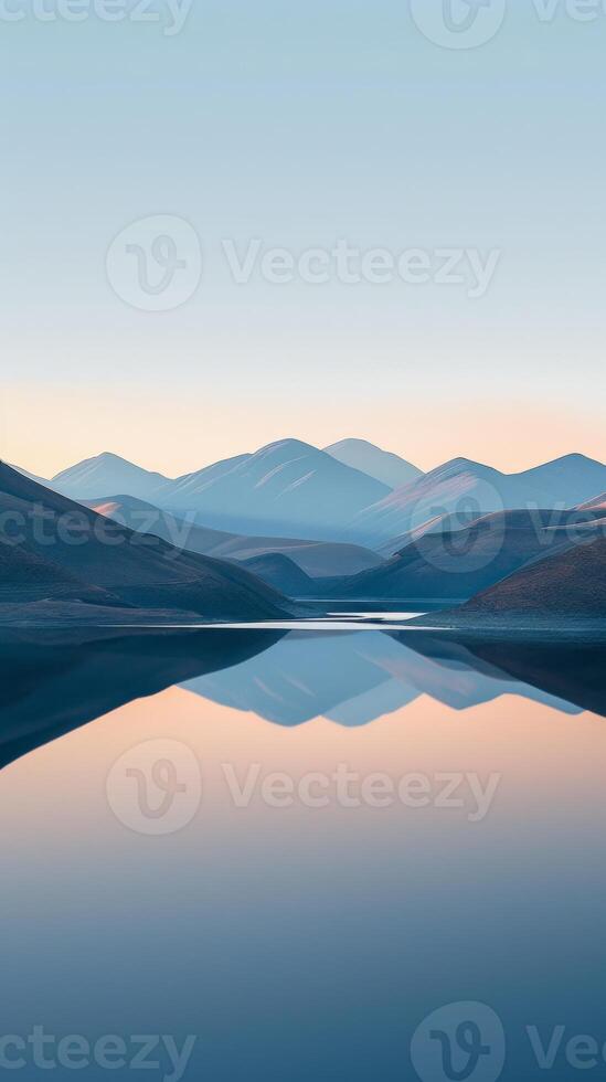 Mountain range reflecting on a still lake at dawn photo