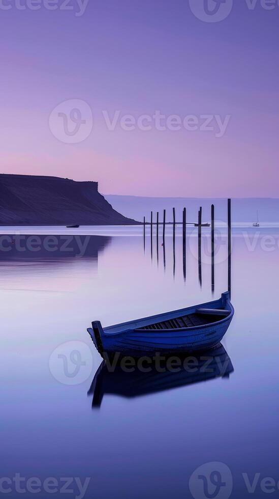 A lone boat rests on the surface of a calm lake at dusk photo