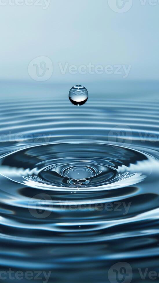 A single water droplet falls into still water, creating concentric ripples photo
