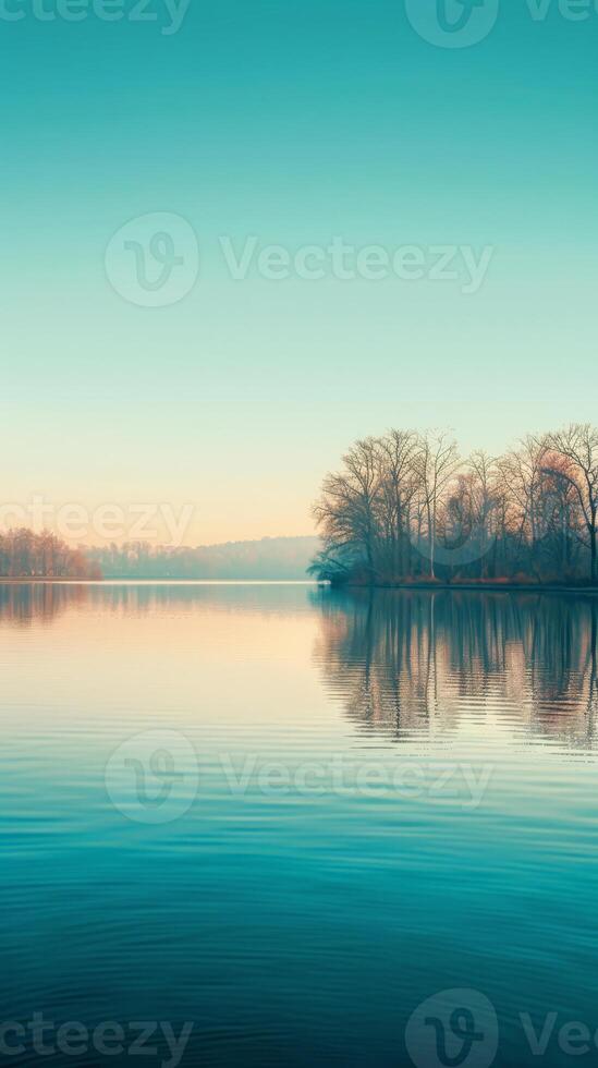 A serene lake with a sliver of trees reflected in the water photo