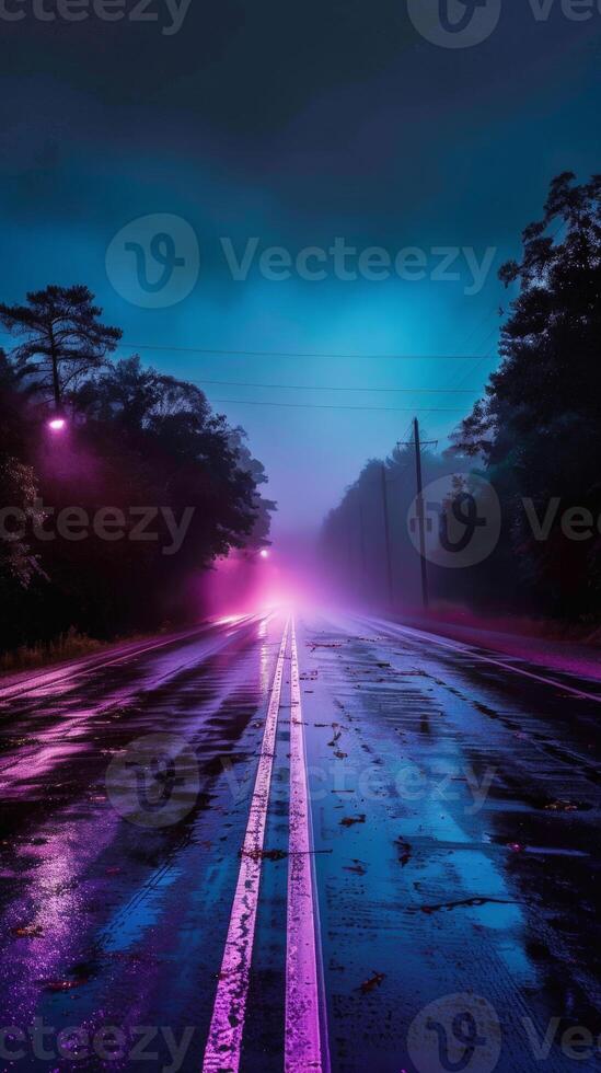 A wet road stretches into the distance with fog and neon lights photo