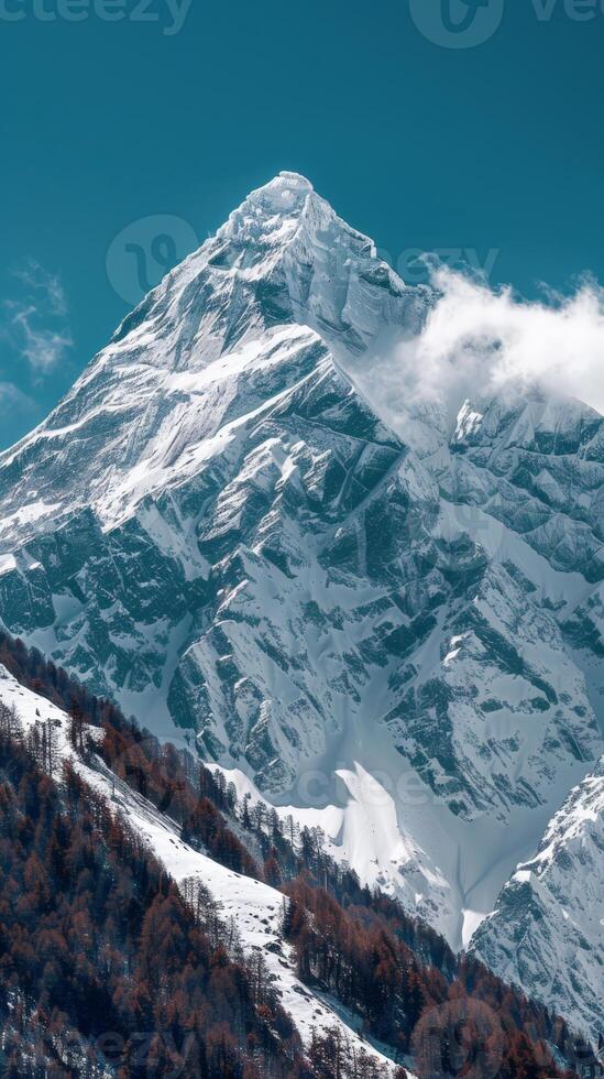 A snow-covered mountain peak dominates the landscape under a clear blue sky photo