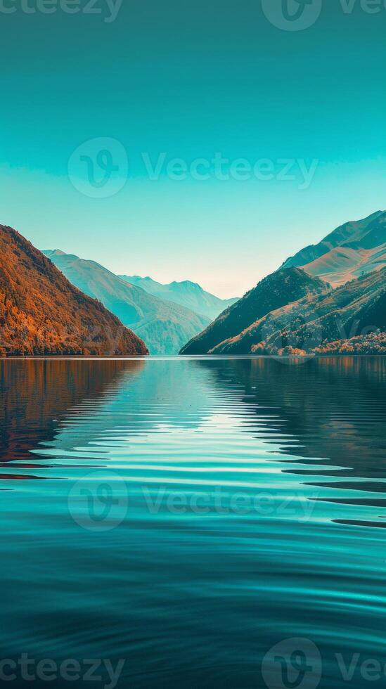 A serene lake reflecting the surrounding mountains under a clear blue sky photo