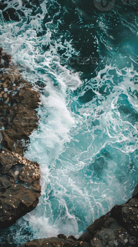 Foamy ocean waves crash against jagged rocks photo