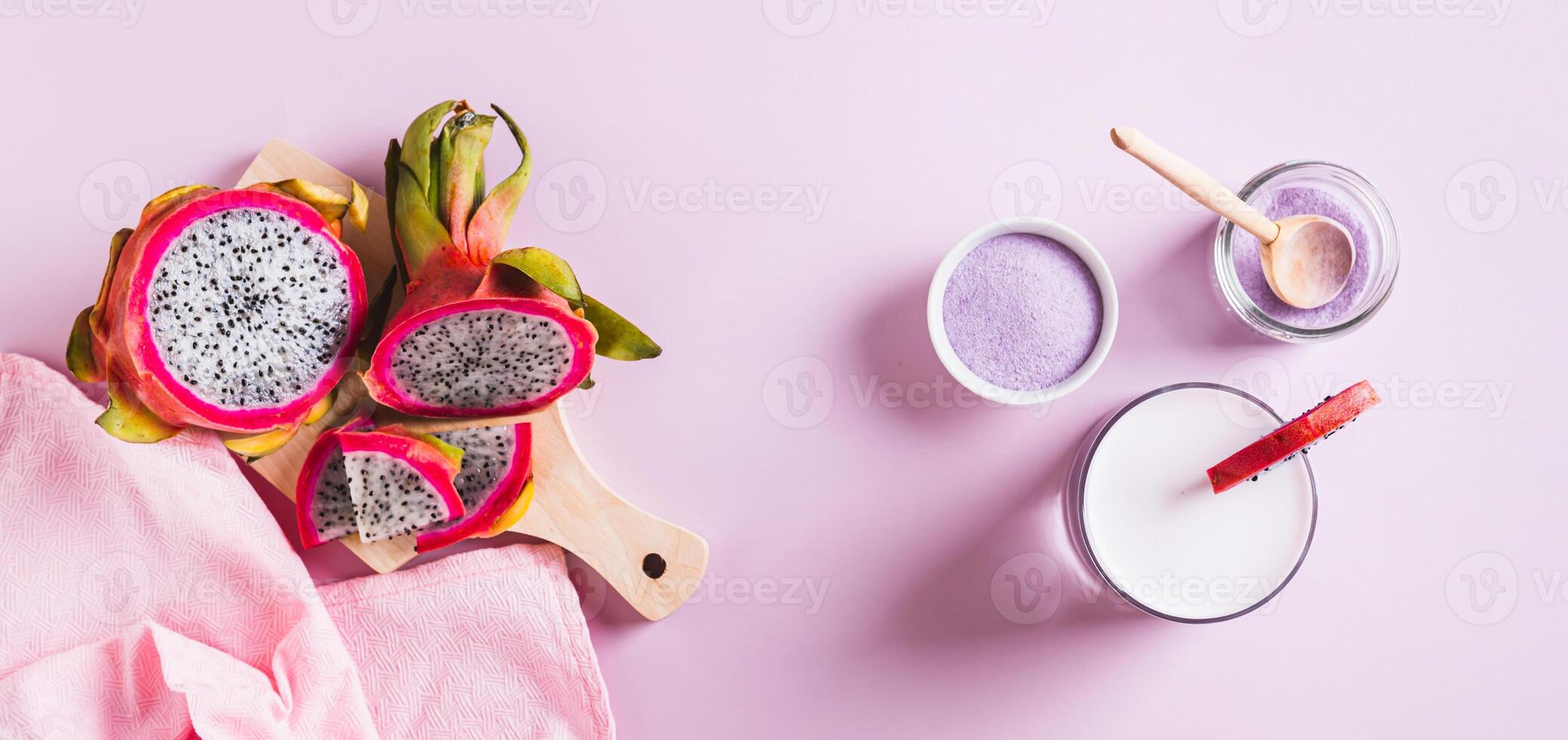 Pink matcha latte in a glass and dragon fruit powder in a bowl on the table top view web banner photo
