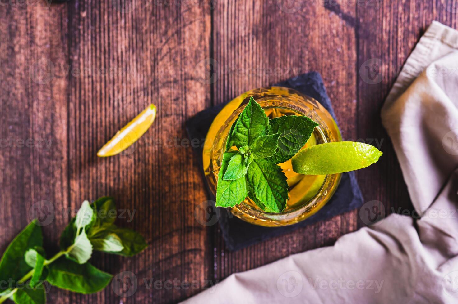 Close up of refreshing iced tea with mint and lime in a glass on the table top view photo